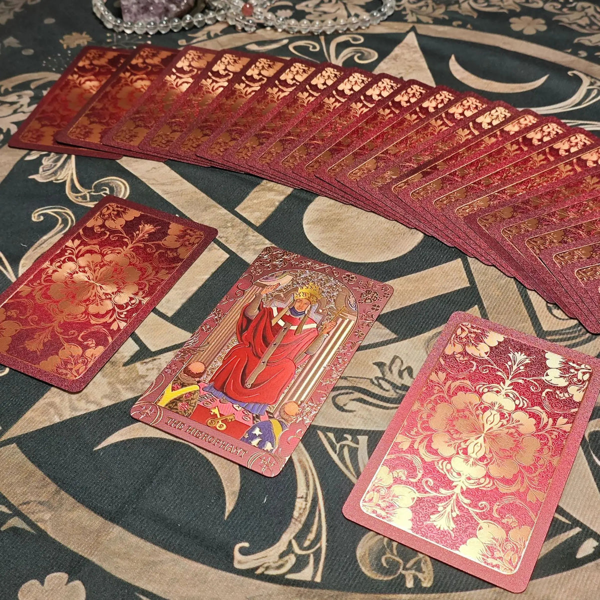 Crimson floral gold foil tarot deck fanned with The Hierophant card