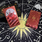 Red gold foil tarot deck with Three of Swords card on astrology cloth